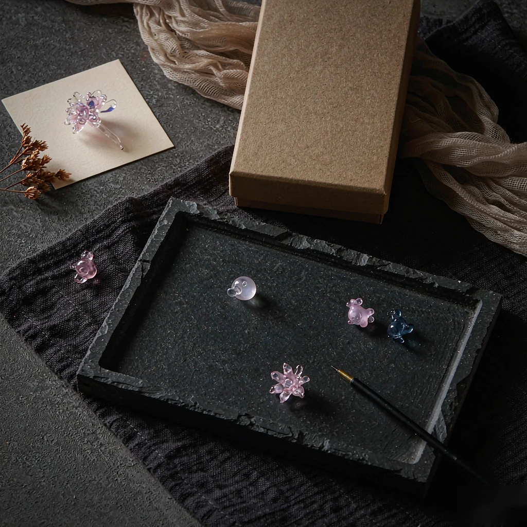 Glass charms and keepsakes laid out beside a kraft gift box
